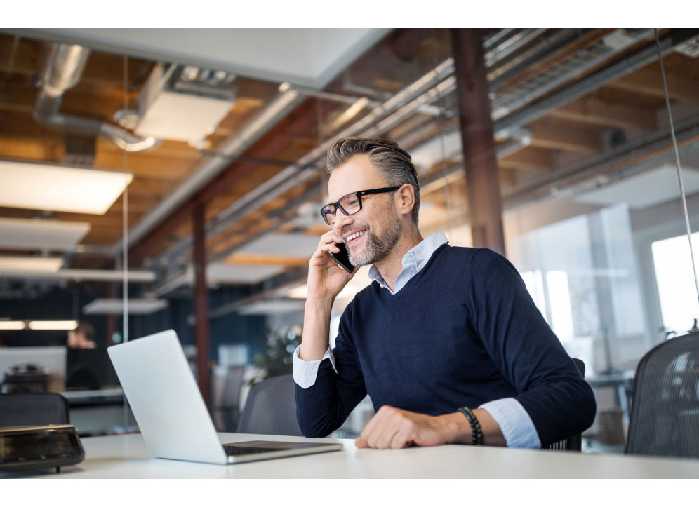 Man looking at laptop while on the phone