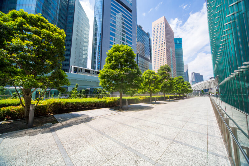 Trees in front of train passing high rise office buildings