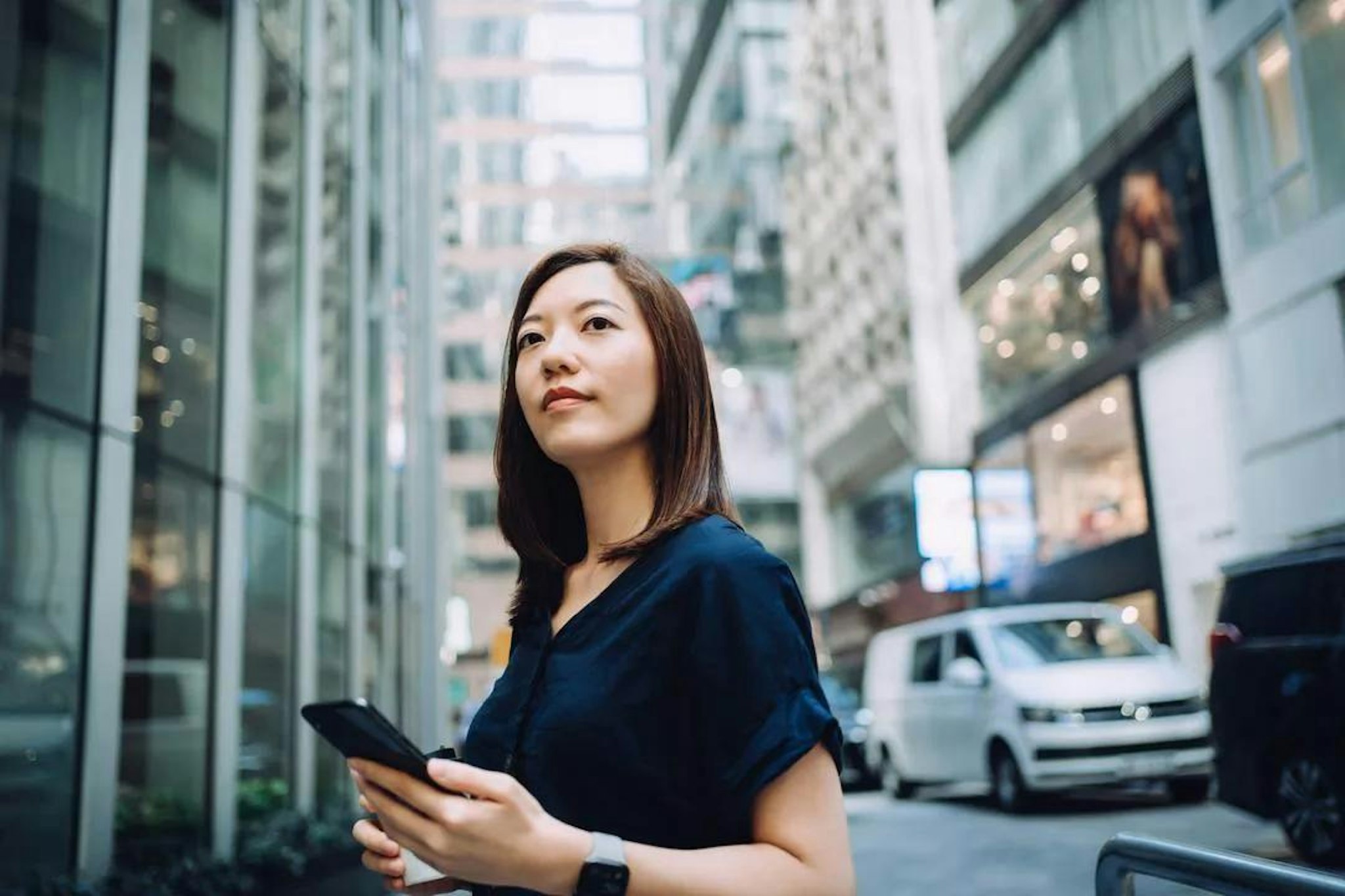 Woman stands in a city street holding her phone